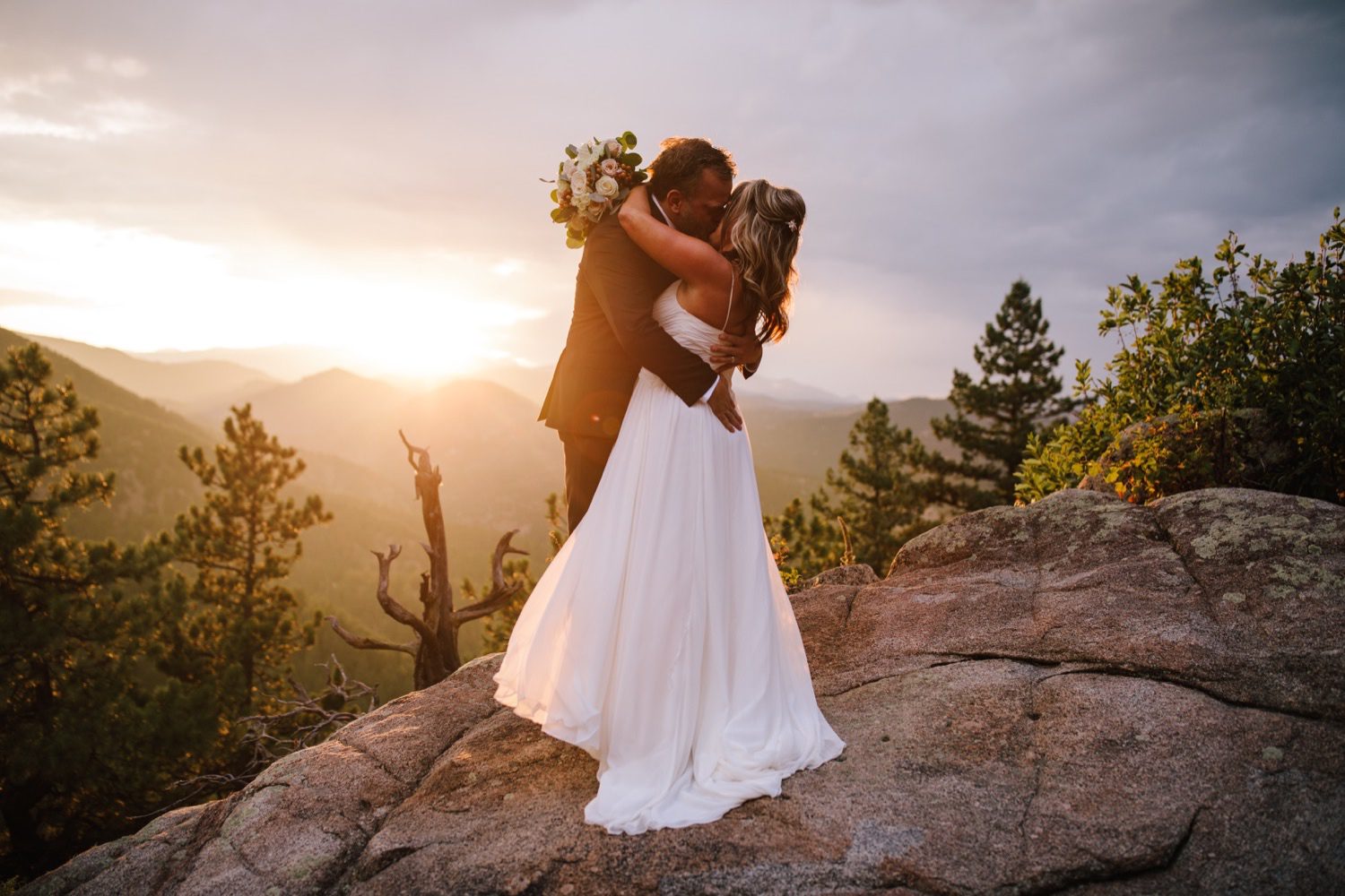 Bride and groom kissing at sunset on a mountain