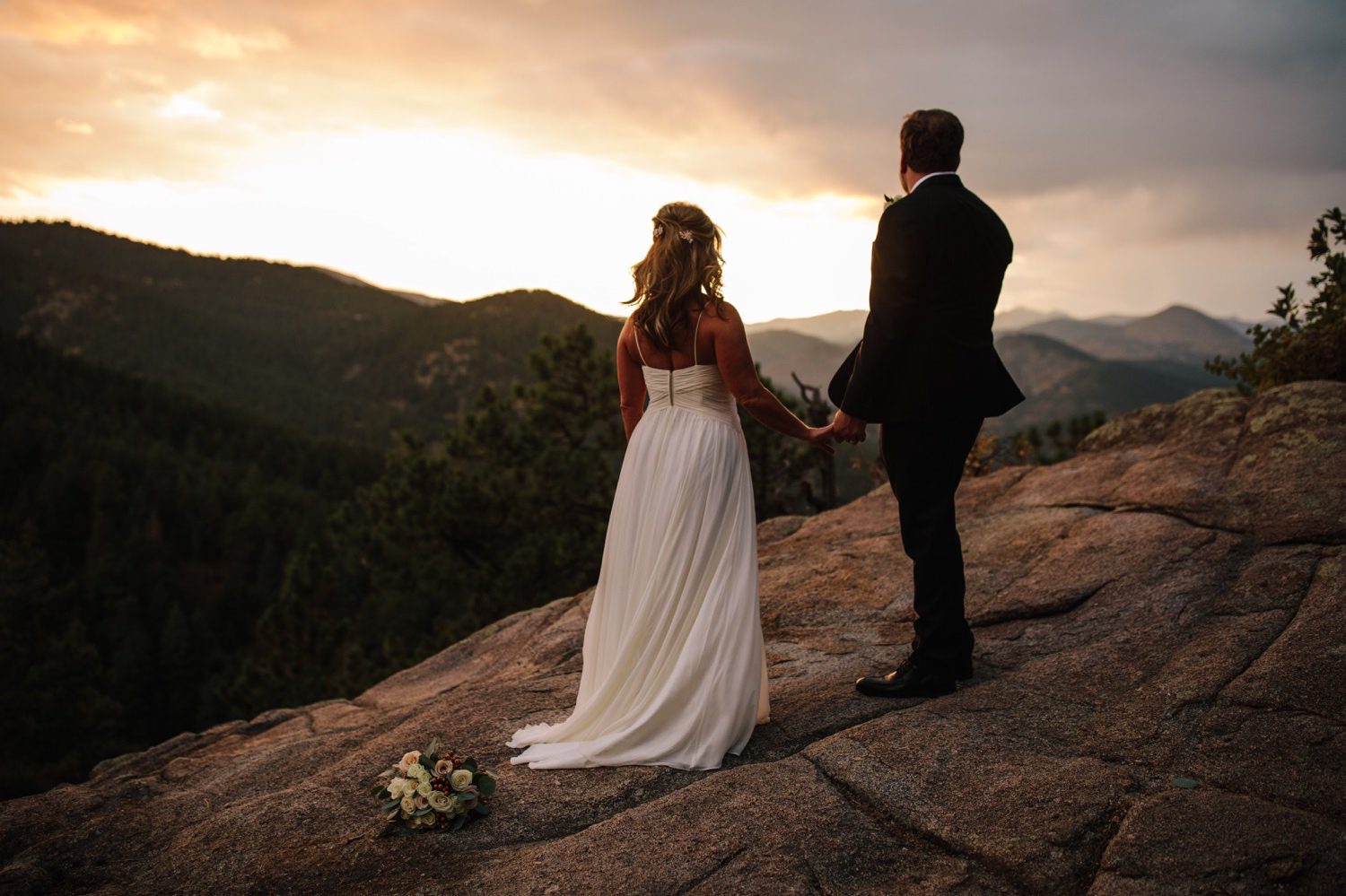 Bride and groom watching Colorado sunset behind the Rocky Mountains