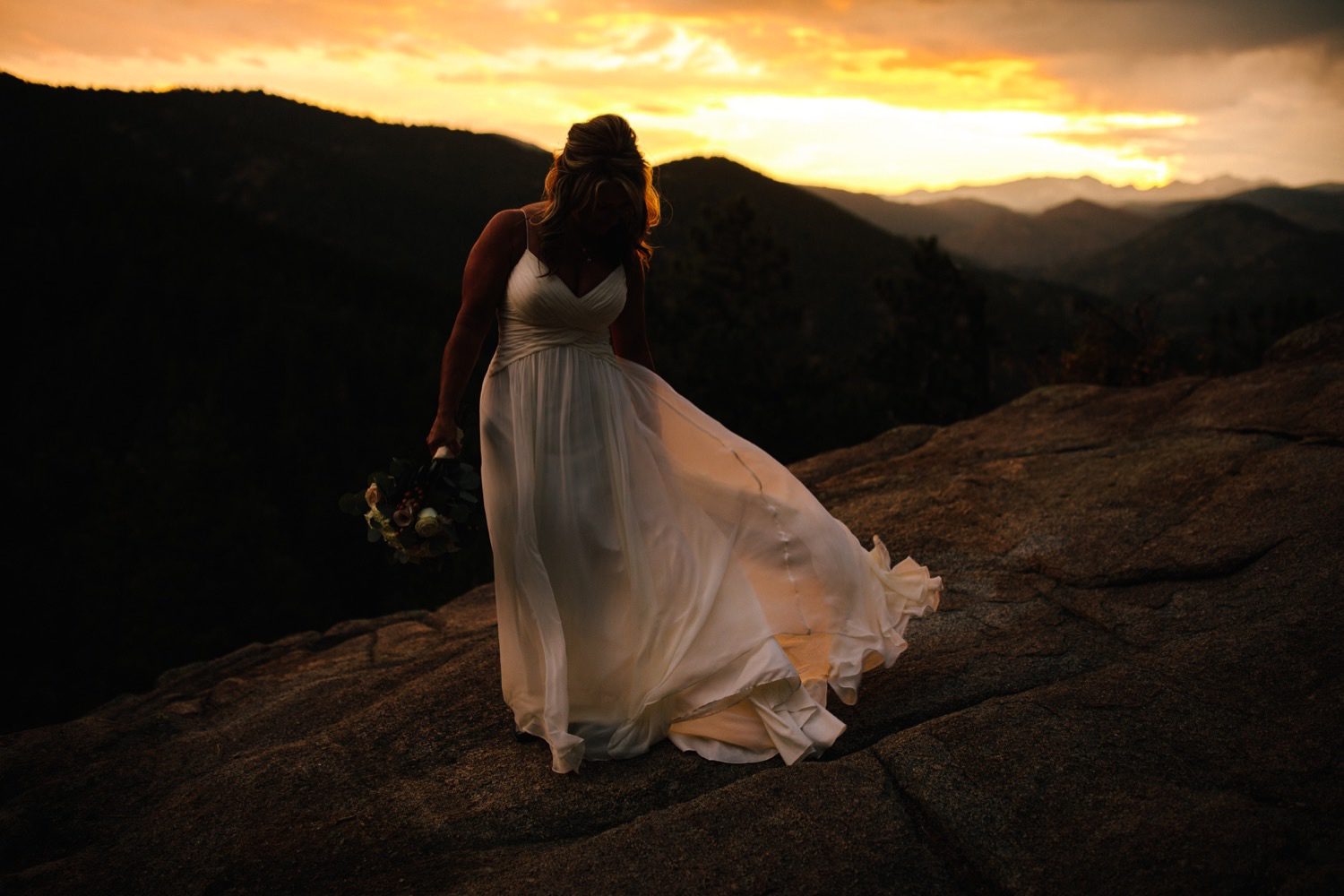 Bride waving dress with Colorado sunset in Rocky Mountains
