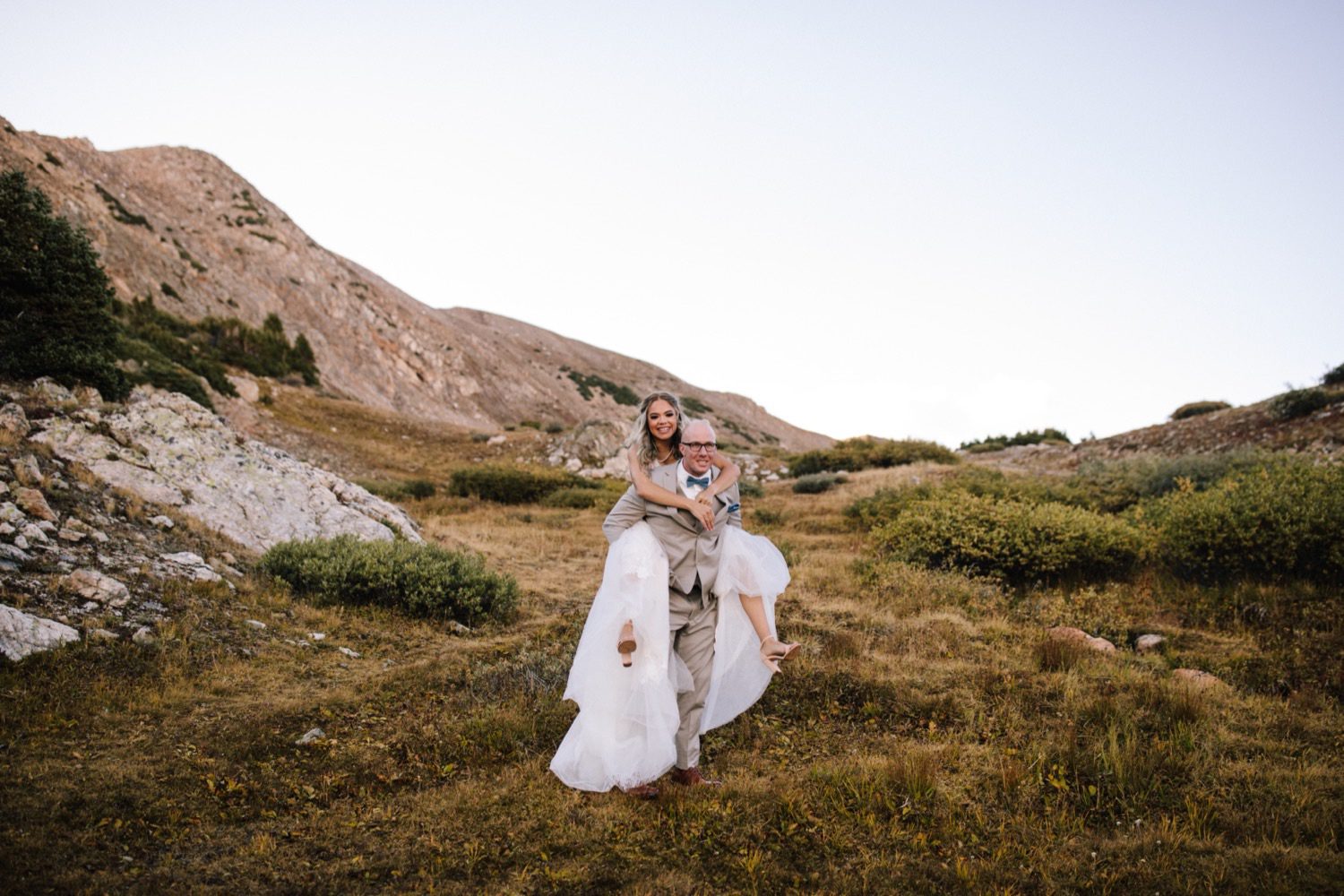 Bride and Groom piggy back ride from Loveland Pass Lake Elopement in Colorado