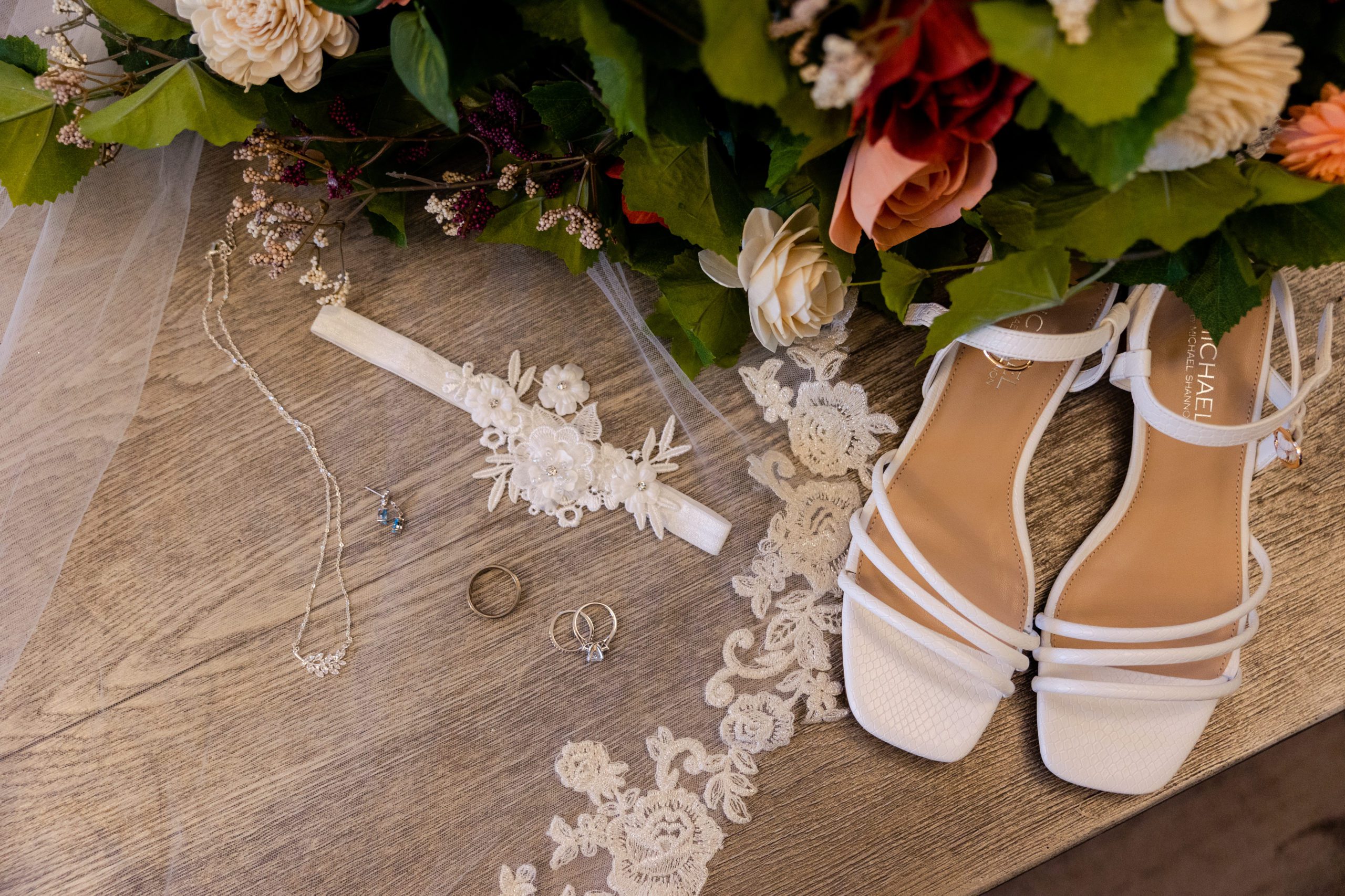 Bridal detail flat lay with garter, wedding rings, bridal jewelry, wedding shoes and Sola Wood Flower bouquet