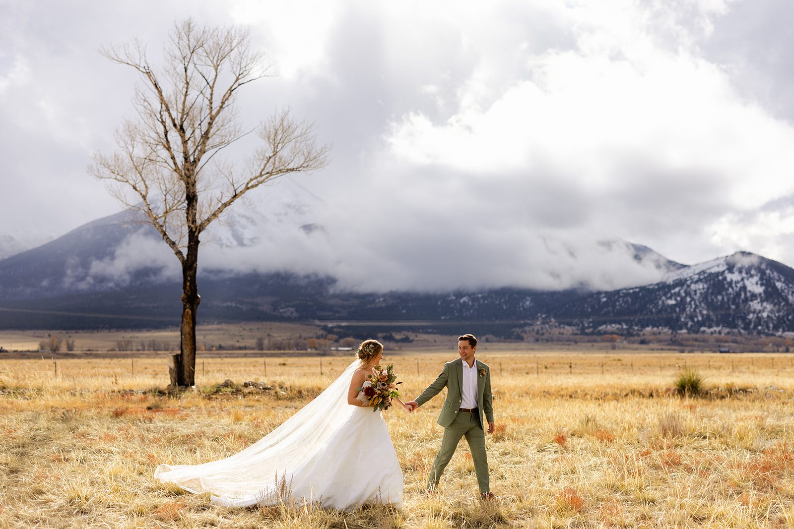 Wedding photography at The Barn at Sunset Ranch in Buena Vista Colorado, Bride with long veil, Green groom suit, Mountain wedding inspiration, Boho wedding bouquet, Bridal updo